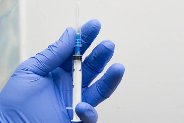istock man holding a syringe in the hand with blue glove 1138886932