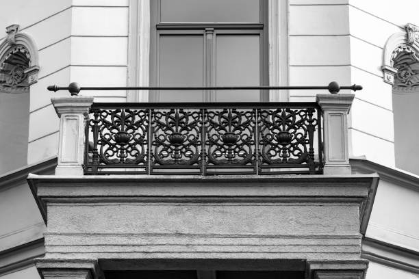 Balcony with cast iron railing in the Baroque style. The facade is light. The railing is painted black.