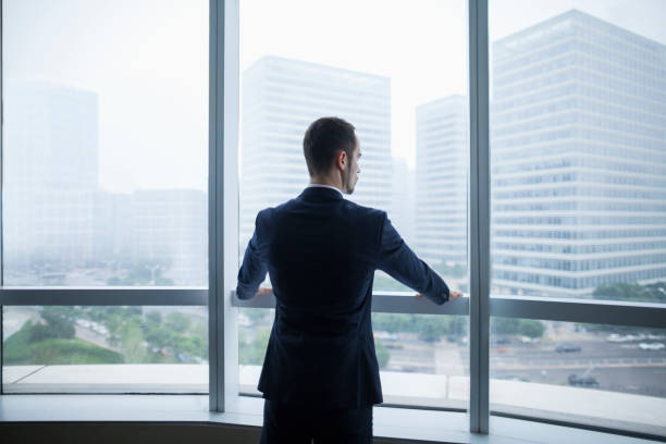 istock Businessman standing at window and viewing city 1138887417