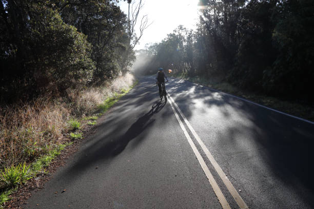 istock Woman rides bicycle down empty road in morning mist 1138888227