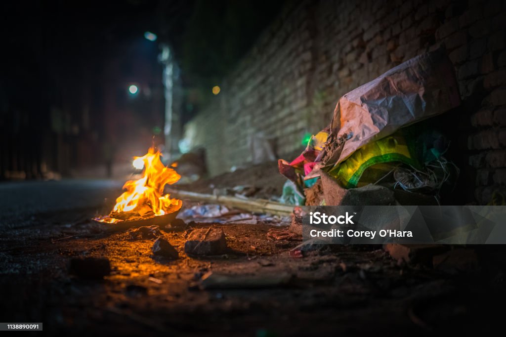 Garbage fire at night Garbage fire at night with burning trash on a dirty street, a metaphor for chaos and current politics Riot Stock Photo