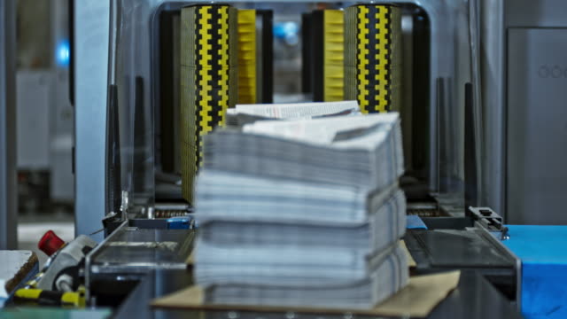 LD Stacks of freshly printed newspapers coming out of the stacking machine