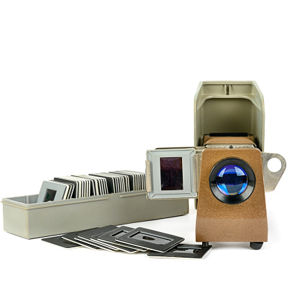 Old slide projector and set of slides isolated on white background. Retro equipment. Free space for text.