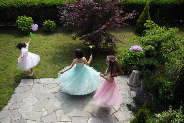 little girls dressed as princesses playing in the garden