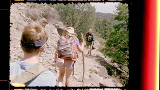 Vintage film camera follows family backpacking along rocky trail at Rio Grande del Norte National Monument on New Mexico hiking trip.
