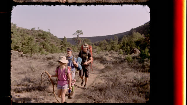 Vintage film camera captures family backpacking along rugged trail at Rio Grande del Norte National Monument on New Mexico camping trip.