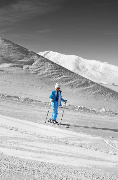 Black and white winter mountains and skier in blue on snowy ski slope at nice sun day. Caucasus Mountains, Shahdagh, Azerbaijan. Selective color effect.