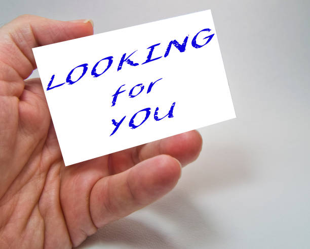 istock Job recruiting advertisement represented by 'LOOKING FOR YOU' texts on cards in man's hands 1138904613