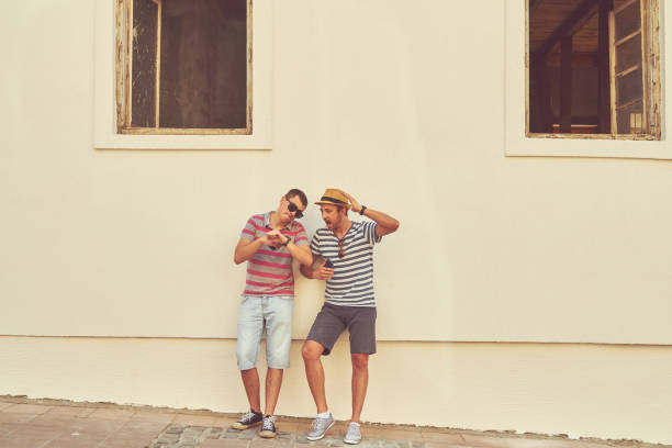 Male friends using cellphone outdoors.