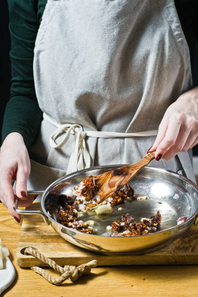 istock The chef prepares onion sauce and sun-dried tomatoes for squid. Black background, side view, kitchen 1138910893