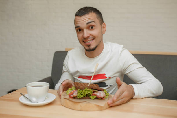 istock Happy young man in cafe will eat sandwich 1138911805