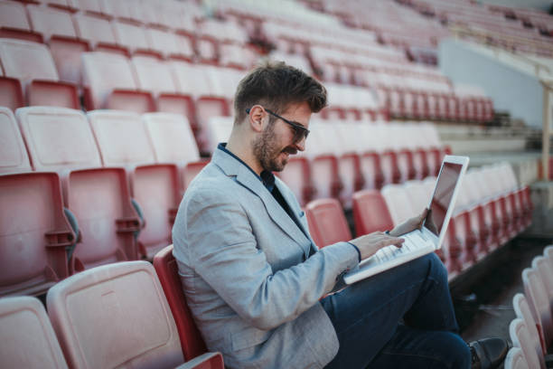 istock Businessman sitting on the stadium and using laptop 1138913643