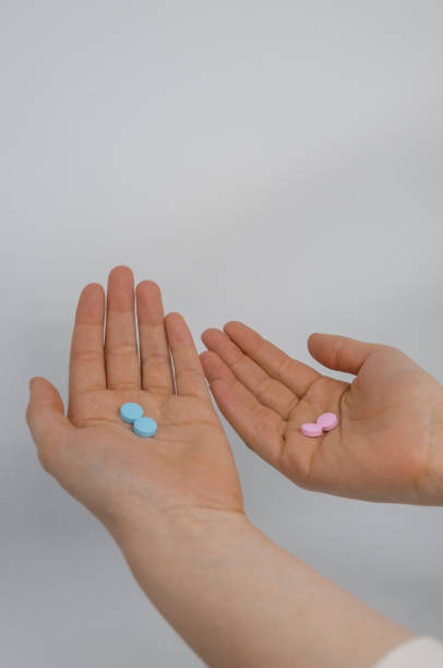istock Two hands with pink and blue pills 1138917328