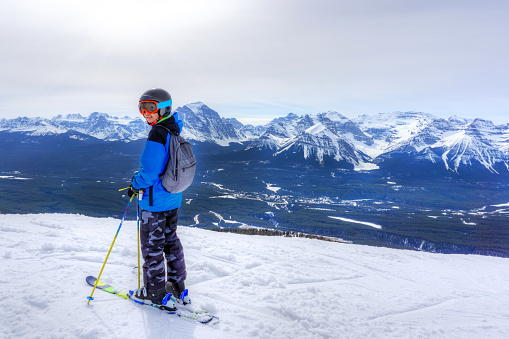 Young skier standing at the edge of a mountain range in Lake Louise at the Canadian Rockies of Alberta, Canada.