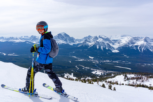 Young skier standing at the edge of a mountain range in Lake Louise at the Canadian Rockies of Alberta, Canada.