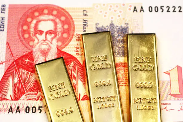 Photo of Three gold bars in macro with a Bulgarian lev bill