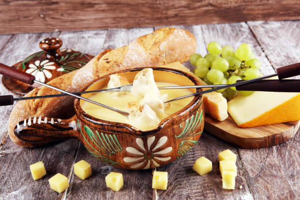 istock Gourmet Swiss fondue dinner on a winter evening with assorted cheeses on a board alongside a heated pot of cheese fondue with two forks dipping 1138929828