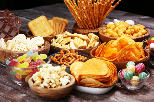 Salty snacks. Pretzels, chips, crackers in wooden bowls. Unhealthy products. food bad for figure, skin, heart and teeth. Assortment of fast carbohydrates food.