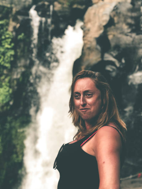 istock beautiful brunette woman and a waterfall 1138934843
