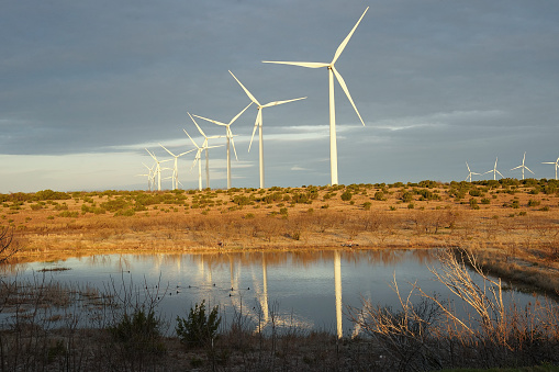 Wind turbines in West Texas with a pond in the foreground.