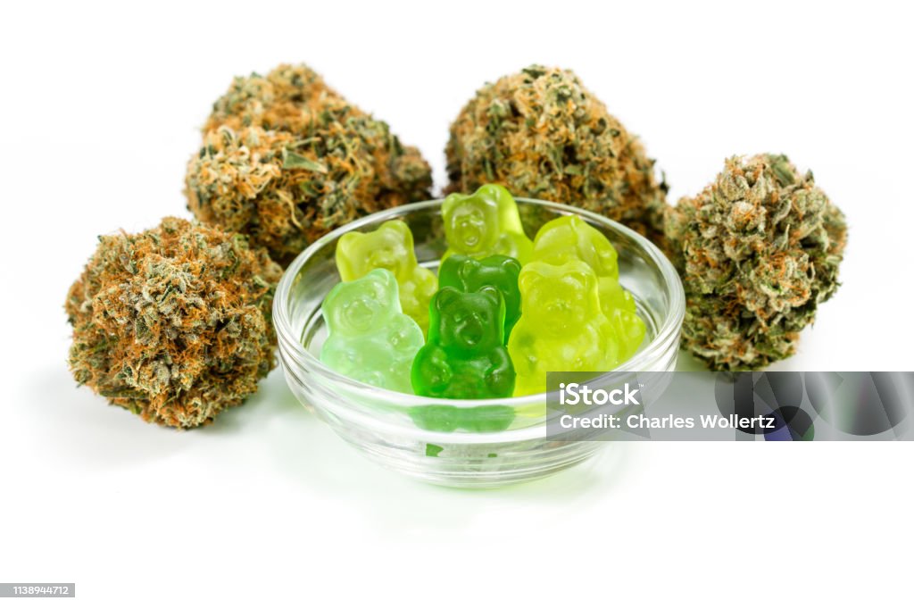 Cannabis owe white clear bowl filled with gummy bears and marijuana buds around isolated on a white background Food Stock Photo