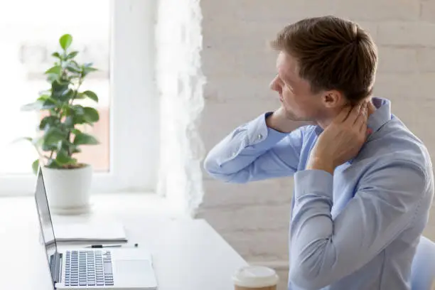 Photo of Millennial tired man having a neck pain
