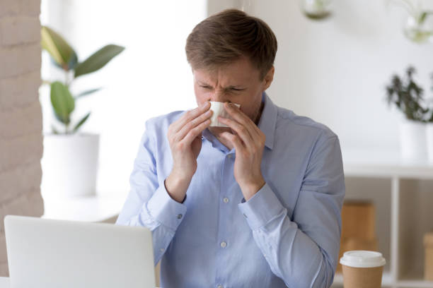 istock Sick man sitting at office and sneeze running nose. 1138947289