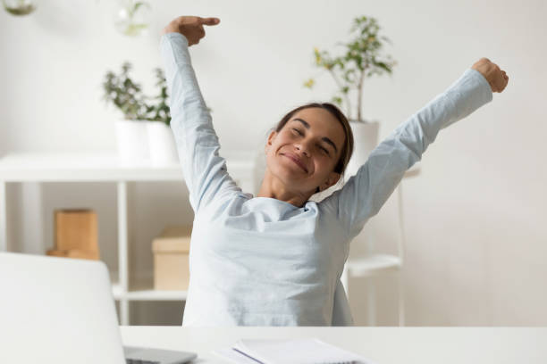 istock Happy woman stretching in front of desk at work 1138947339