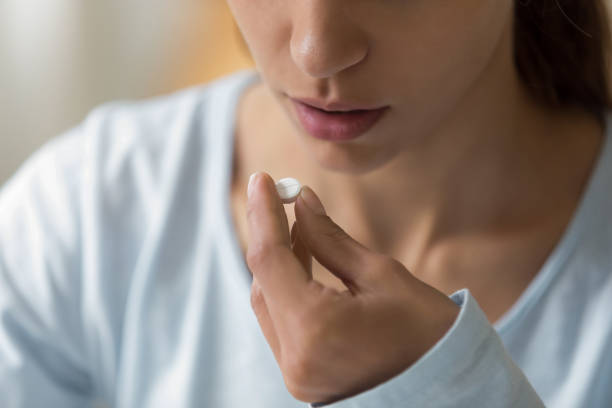 closeup image of woman face and pill in hand - birth control pill imagens e fotografias de stock