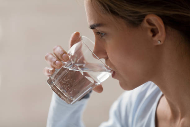closeup profile portrait of woman drinking pure water from glass - thirsty imagens e fotografias de stock