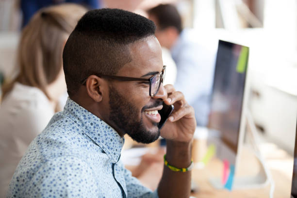 istock Smiling african employee talking on phone with client 1138949135