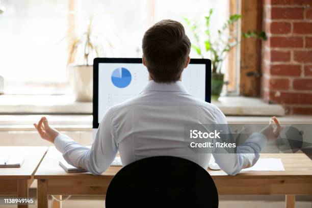 Rear View Businessman Sitting At Desk Opposite Pc Doing Yoga Stock Photo - Download Image Now