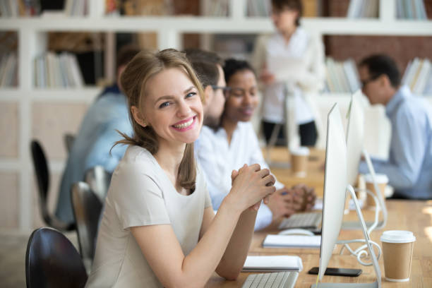 istock Employee female sitting at desk opposite pc looking at camera 1138949163