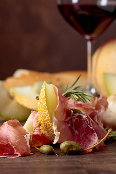 istock Prosciutto with melon, capers and rosemary on a old wooden table. 1138950686