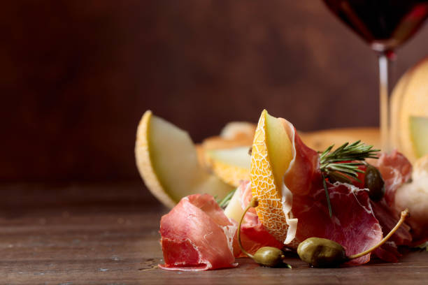 istock Prosciutto with melon, capers and rosemary on a old wooden table. 1138950693