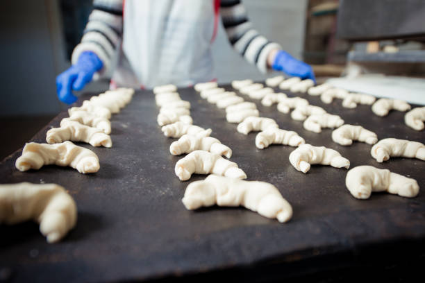 Baker laying the raw dough croissants on a baking tray