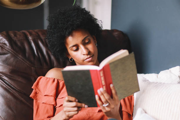 retrato de una joven mujer relajándose y leyendo en su apartamento en el centro de los ángeles - women solitude enjoyment 20s fotografías e imágenes de stock