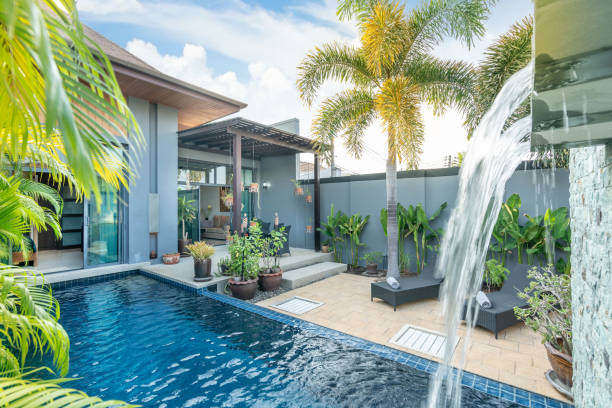 home or house building  Exterior  and interior design showing tropical pool villa with green garden, with sun bed and blue sky stock photo