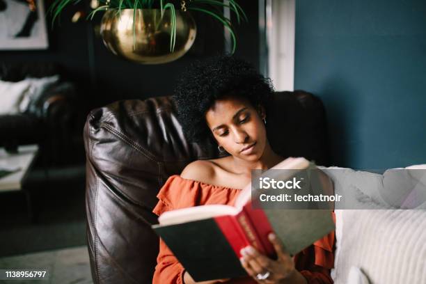 Portrait Of A Young Woman Relaxing And Reading In Her Downtown Los Angeles Apartment Stock Photo - Download Image Now