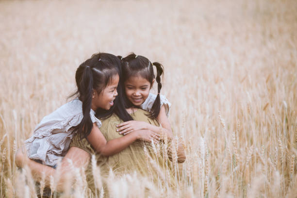 ragazze asiatiche felici che abbracciano la madre e si divertono a giocare con la madre nel campo d'orzo - oat farm grass barley foto e immagini stock