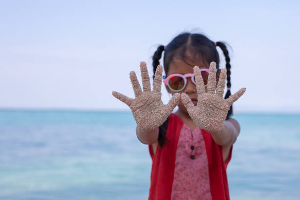 Asian child hands with sand having fun on the beach
