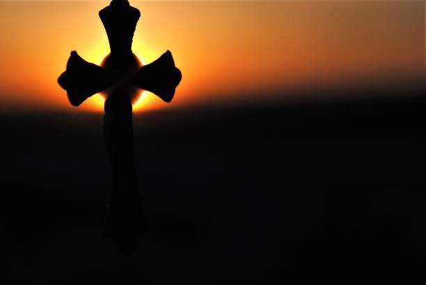 istock Christian Cross Silhouette with a Glowing Sun in the Background 1138973129