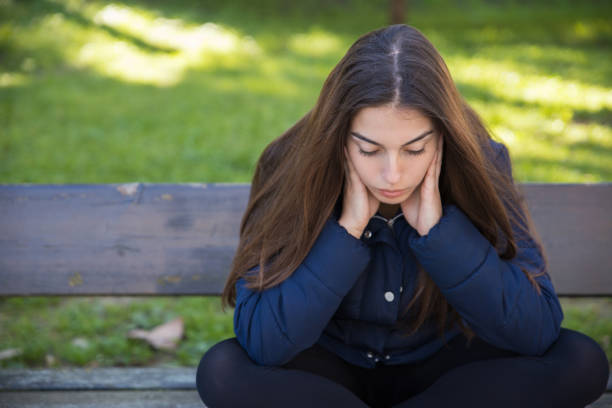 istock Pensive pretty woman sitting on bench in park 1138976473