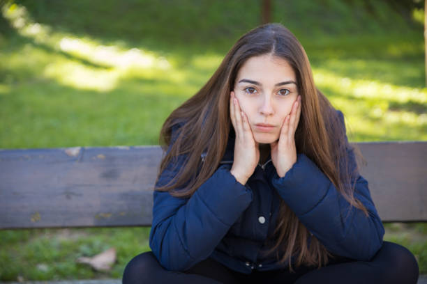 istock Pensive pretty woman posing at camera in park 1138976475