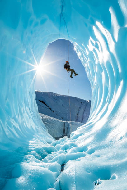 el joven se convierte en una enorme cueva de hielo en el glaciar en la naturaleza de alaska - ice climbing fotografías e imágenes de stock