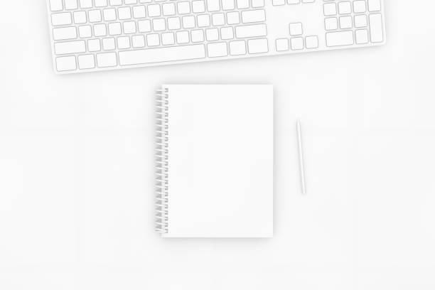istock Top view of notebook with pencil and keyboard on white background 1138979430