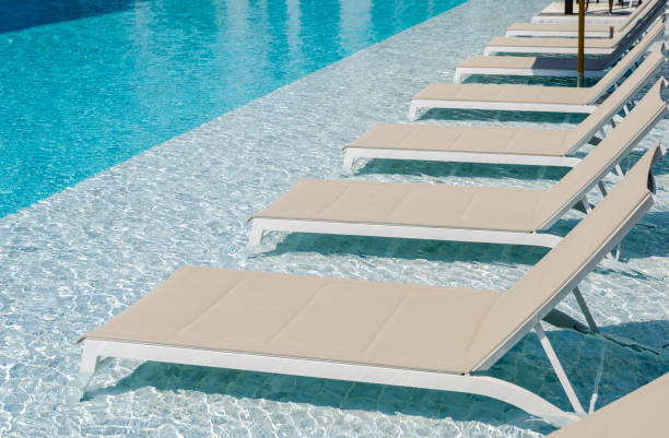 Swimming pool with chaise loungers Turquoise swimming pool with clean water and sunbeds chaise longue stock pictures, royalty-free photos & images