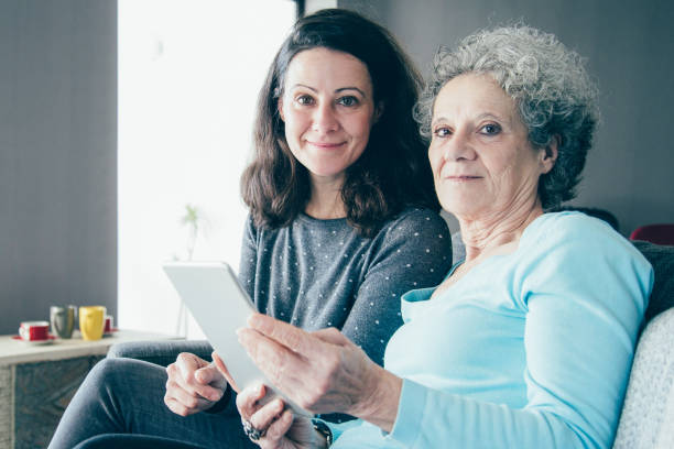 istock Smiling elderly woman and daughter browsing on tablet computer 1138981942