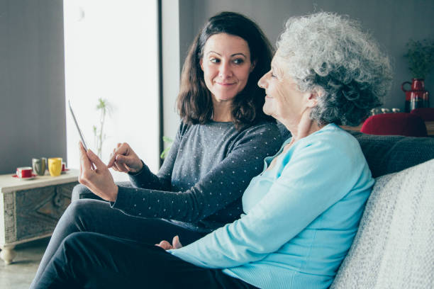 웃는 노인 여자와 그녀의 딸 태블릿 컴퓨터를 사용 하 여 - family domestic life senior adult computer 뉴스 사진 이미지