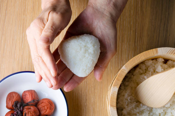Japanese senior woman holding rice ball and rice cooked with umeboshi stock photo